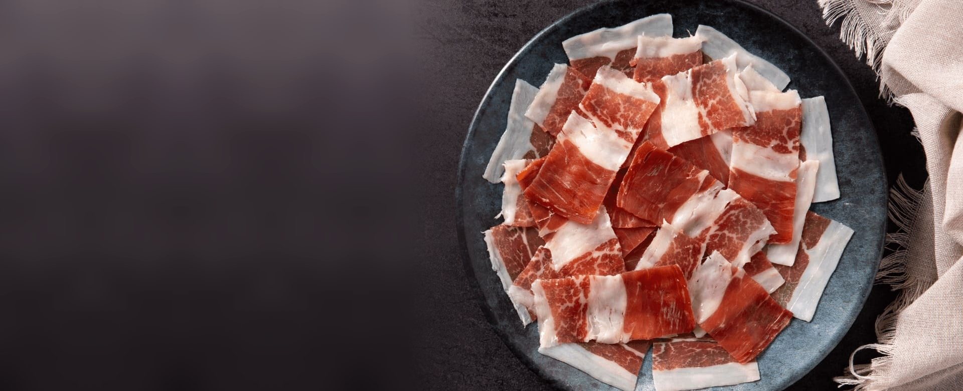 Plato de pétalos de jamón ibérico sobre una mesa de pizarra
